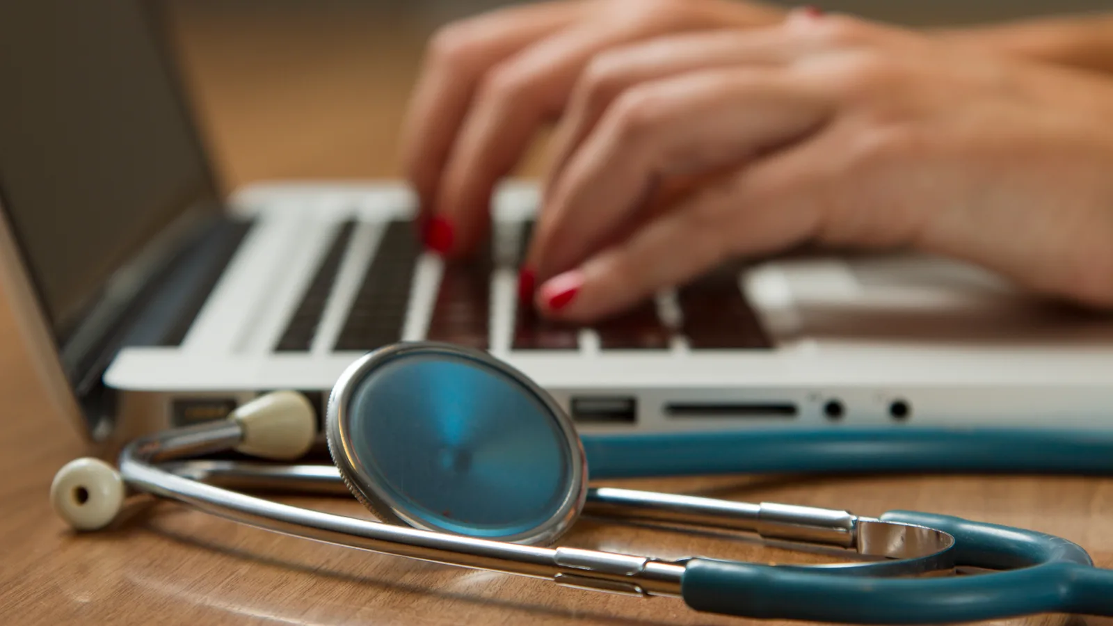 Un stéthoscope posé devant un ordinateur portable, symbole de l’accès aux soins de première ligne.